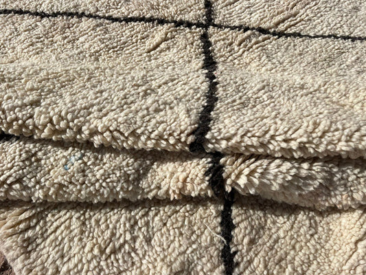 Close-up of a soft wool Moroccan rug with black line detailing and thick texture