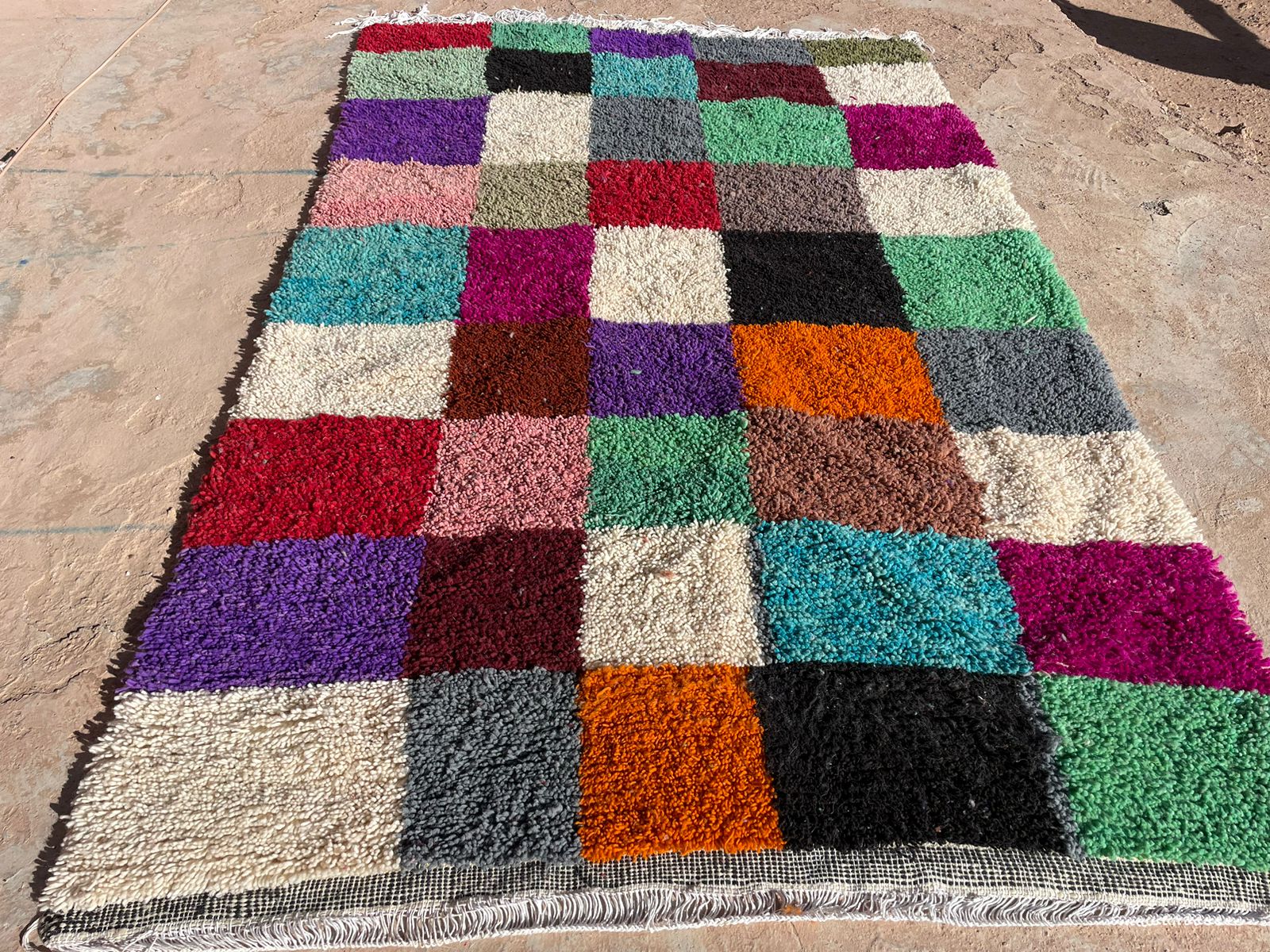 Outdoor view of handmade Moroccan shag rug with multicolor checkered wool pattern, 5x8 feet