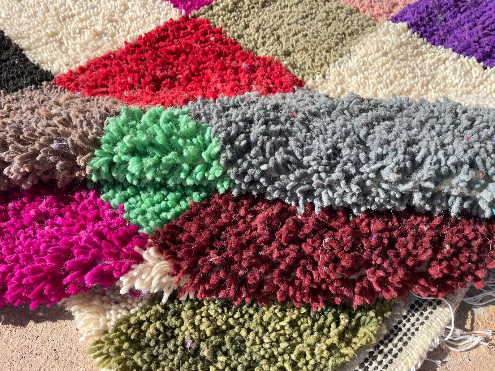 Close-up of handmade Moroccan shag rug showing colorful wool texture and checkered pattern in vibrant tones