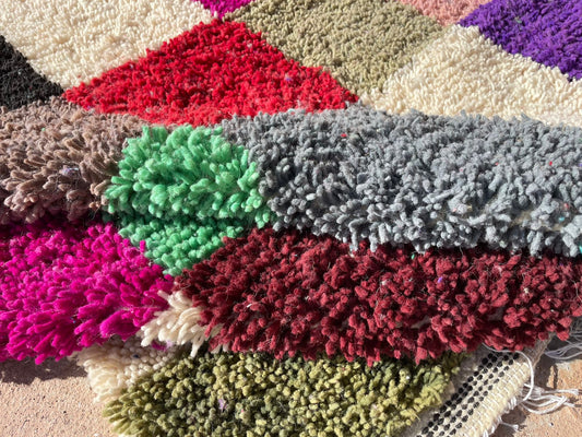 Close-up of handmade Moroccan shag rug showing colorful wool texture and checkered pattern in vibrant tones