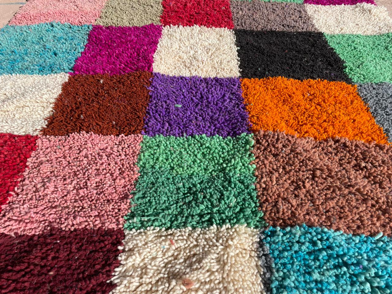 Detailed close-up of handmade Moroccan shag rug with vibrant multicolor checkered wool texture