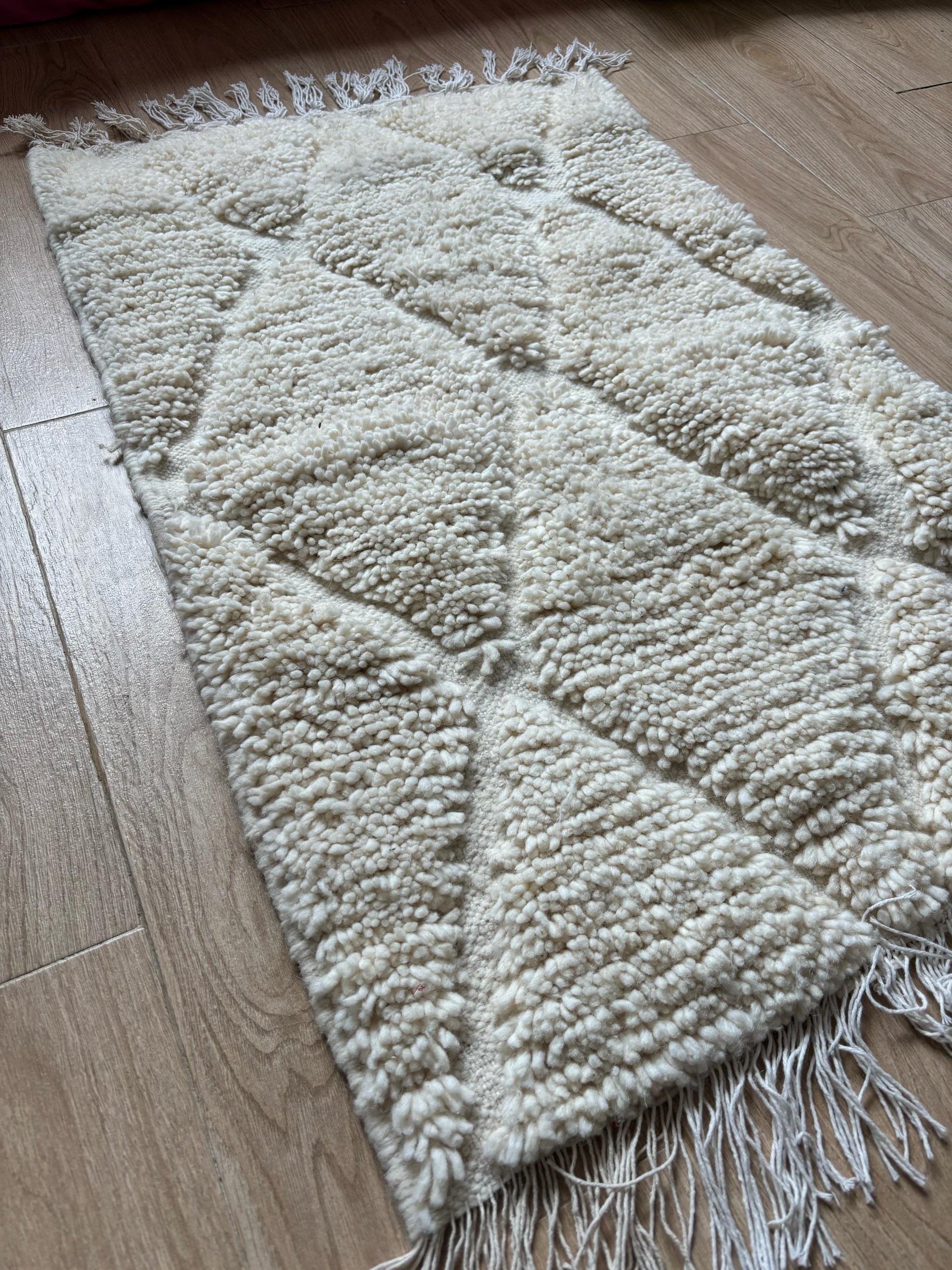 Ivory Moroccan runner rug with raised diamond texture, handcrafted from wool and styled on a wooden floor by YAMA Carpet.