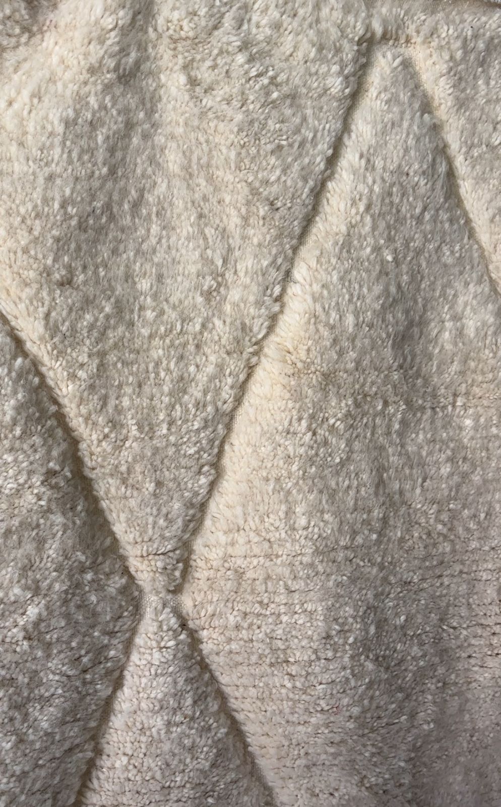 Macro close-up of handmade Moroccan wool rug in cream with diamond stitched texture and high pile softness