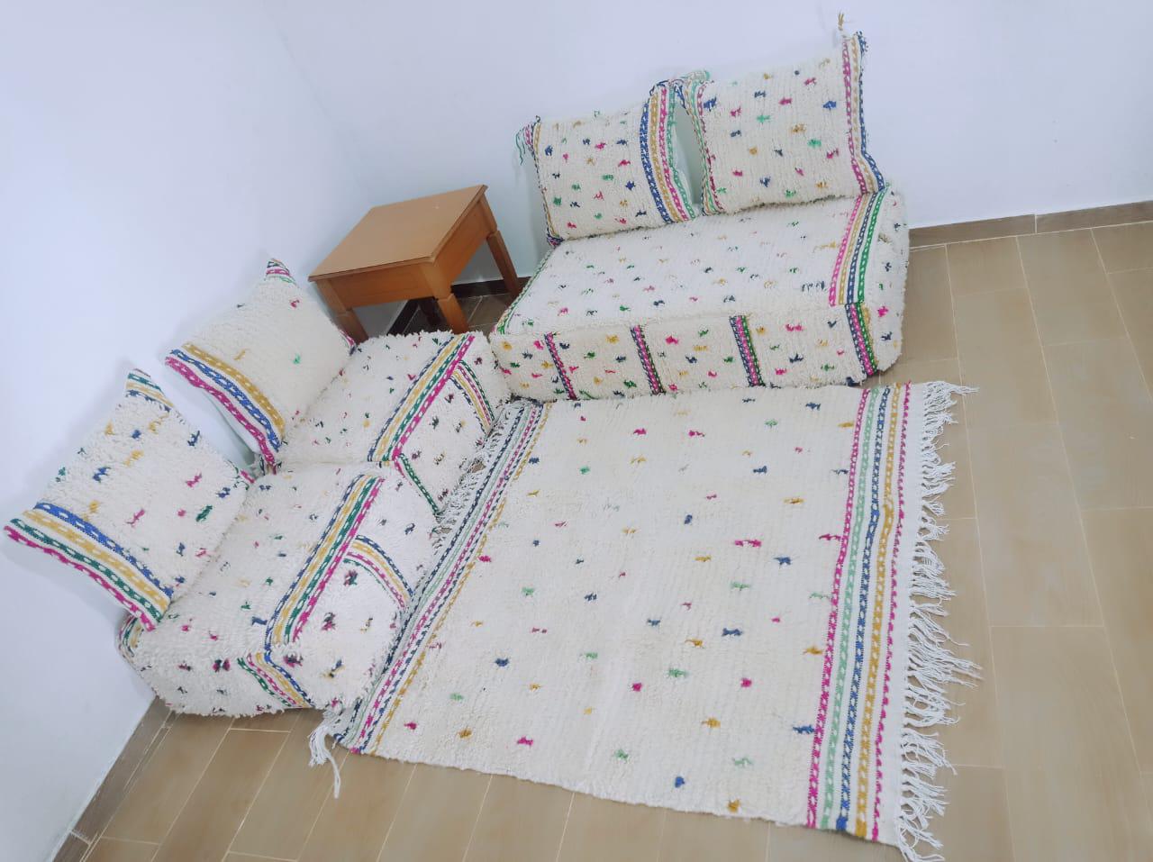 Ivory Moroccan boho floor sofa set with colorful handmade wool rug and embroidered Berber-style accents.