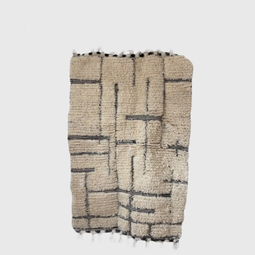 Flat lay of handmade Moroccan rug in cream with black geometric lines, wool material