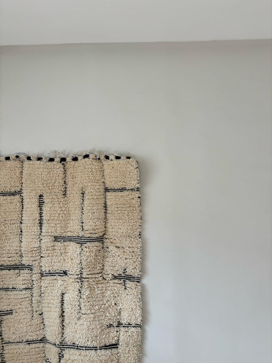Modern Moroccan wool rug with cream base and black geometric lines, styled as wall hanging