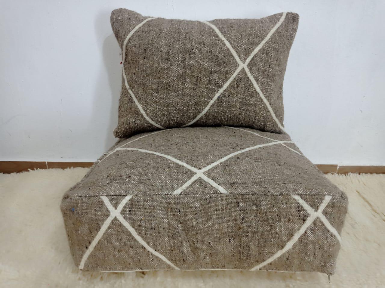 Handwoven Moroccan pouf chair in natural brown wool with a minimalist Berber-style white line pattern.