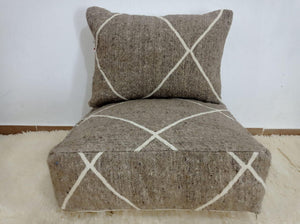 Handwoven Moroccan pouf chair in natural brown wool with a minimalist Berber-style white line pattern.