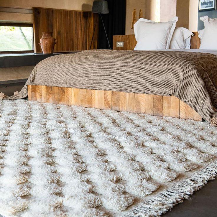 Cream Moroccan wool rug with 3D checkered texture styled in modern bedroom with wood bed