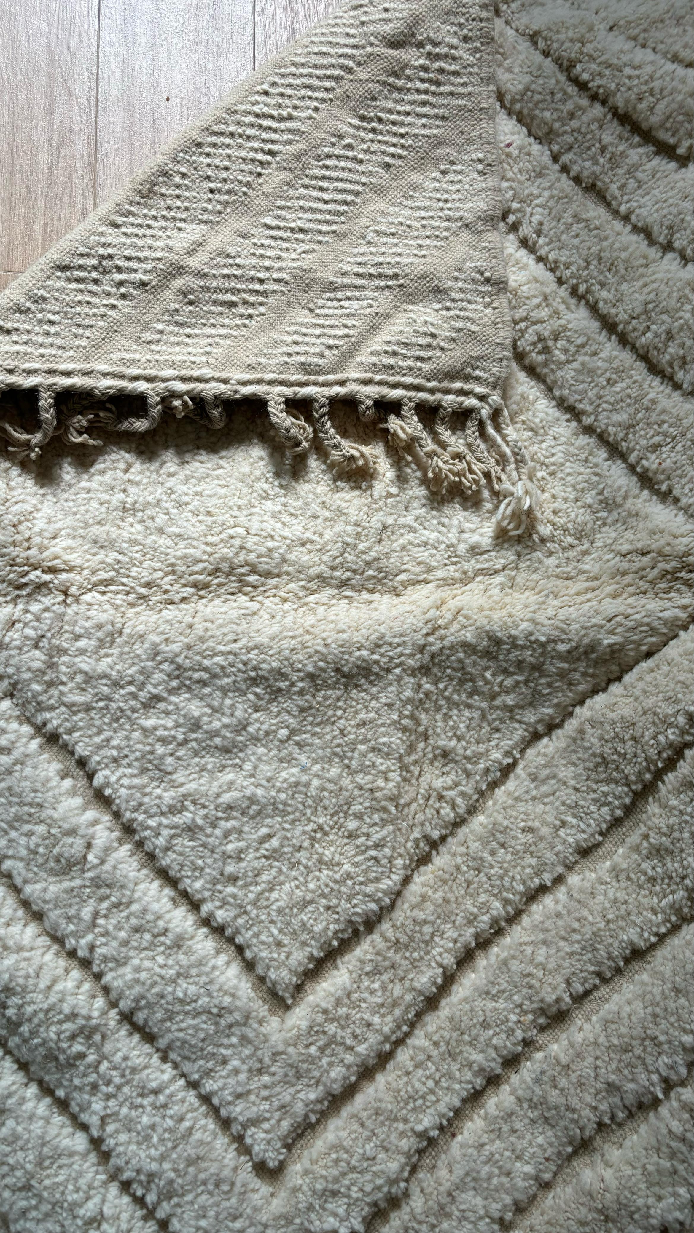 Close-up of cream Moroccan rug showing front pile and backside weave with fringe detail