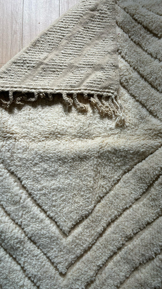 Close-up of cream Moroccan rug showing front pile and backside weave with fringe detail