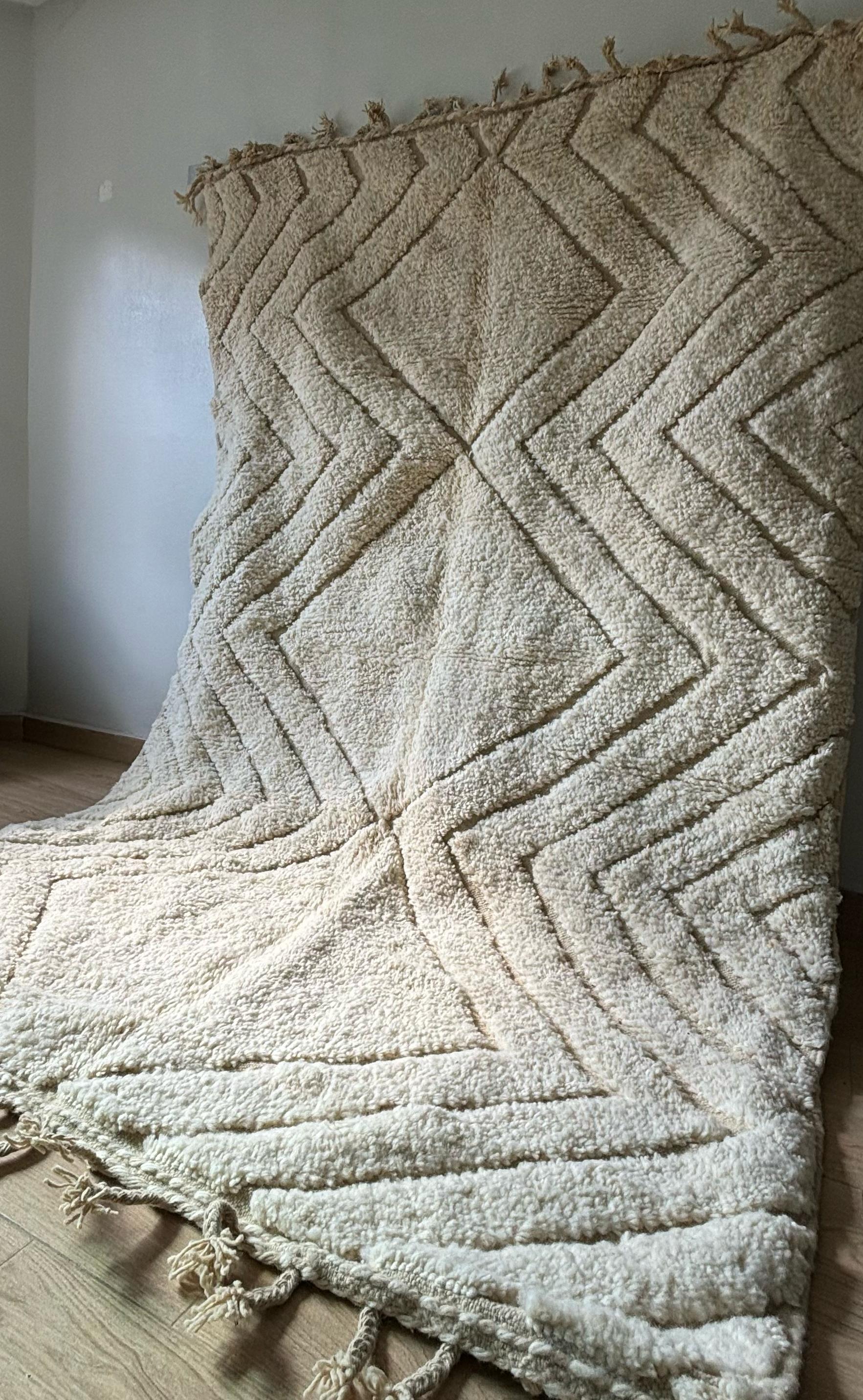 Soft cream Moroccan wool rug with geometric chevron pattern, side view on wooden floor, 5x8 feet