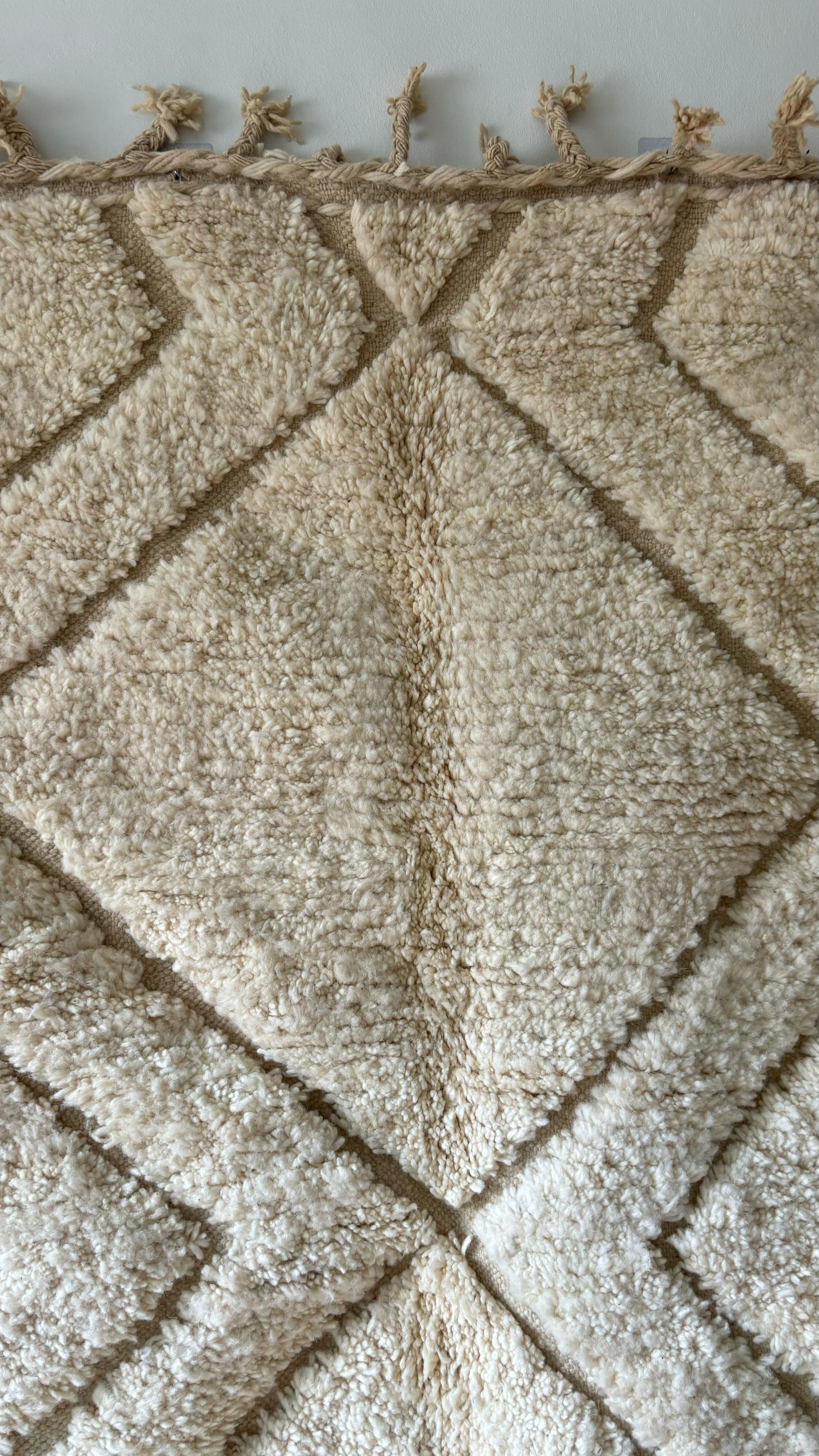 Close-up of cream Moroccan wool rug with chevron diamond pattern and knotted fringe, 5x8 feet