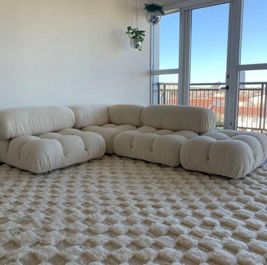 Cream Moroccan wool rug with 3D checkered texture styled in bright living room with tufted sofa