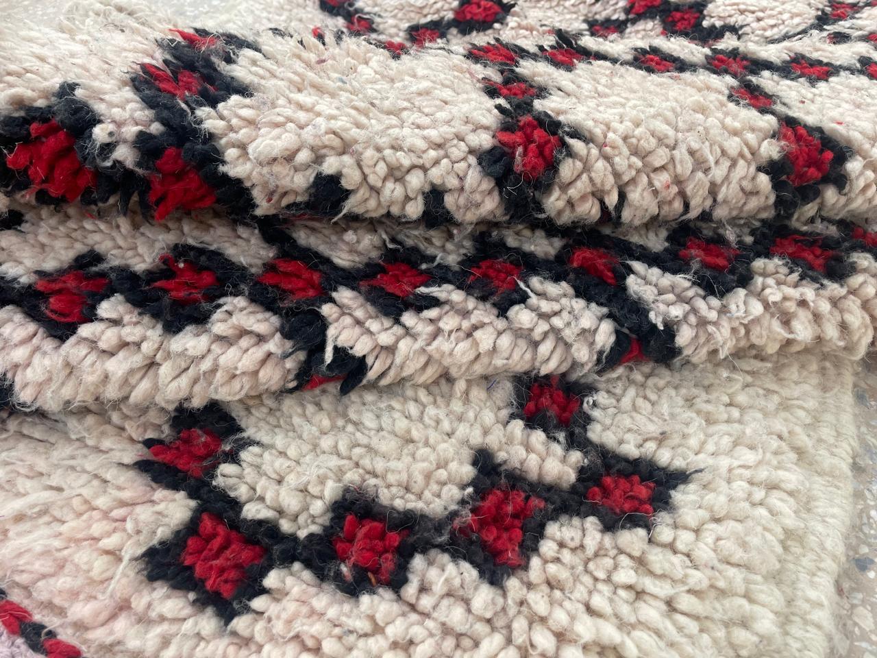 Folded Moroccan runner rug showing thick wool texture and black burgundy diamond pattern