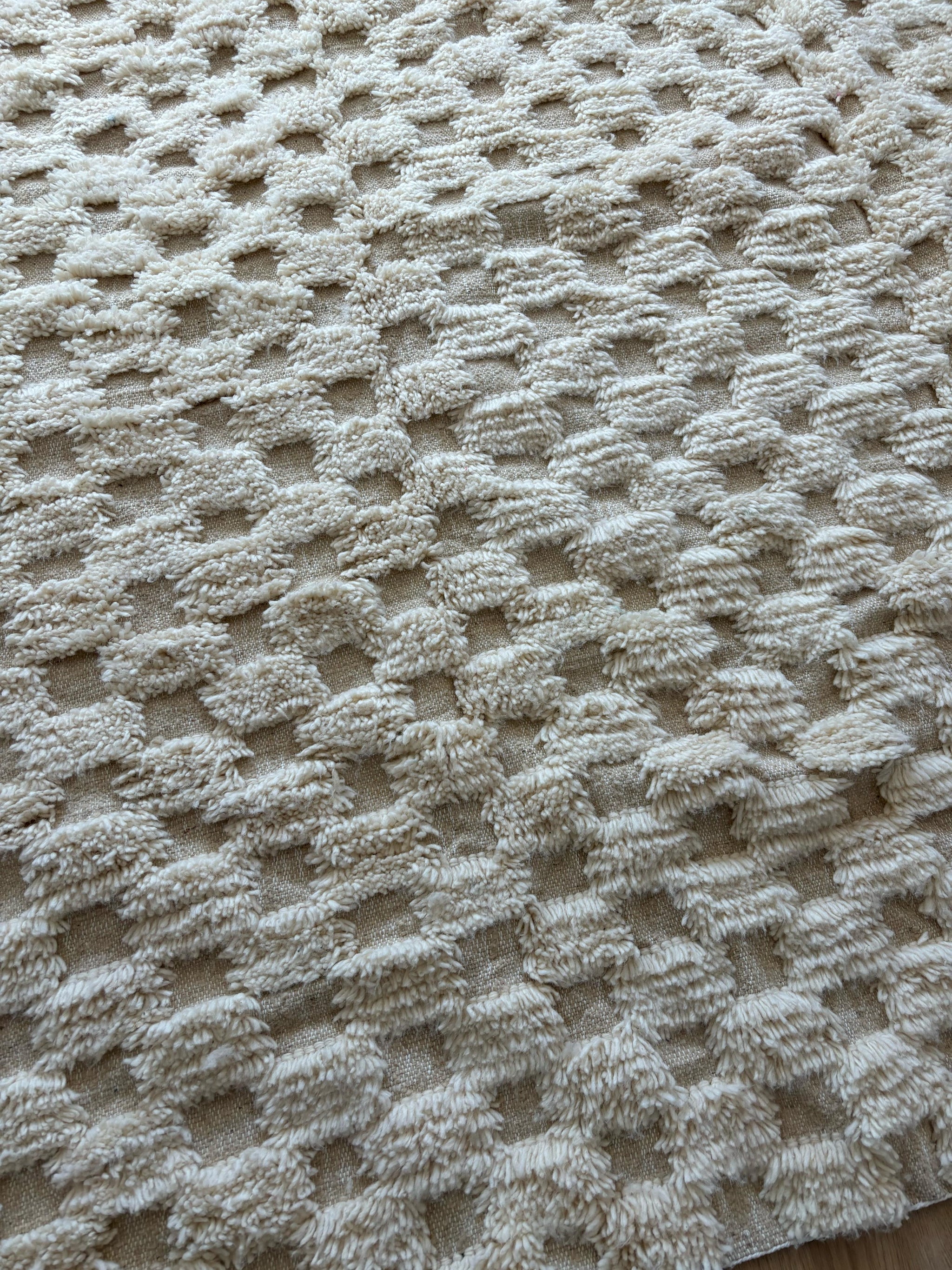 Close-up of handmade Moroccan wool rug in cream with 3D checkered pattern and soft texture