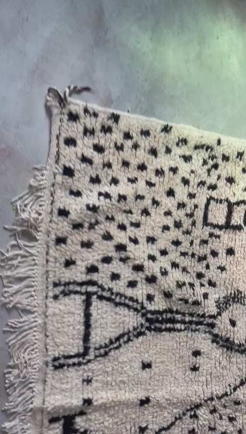Close-up video showing handmade Moroccan wool rug with black and white patterns and detailed texture
